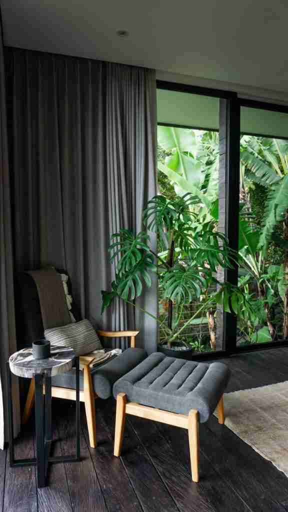 Cozy chair surrounded by monstera plants in a stylish hotel room at Munduk Cabins, Bali — tropical interior vibes featured on Bohemian Bela.