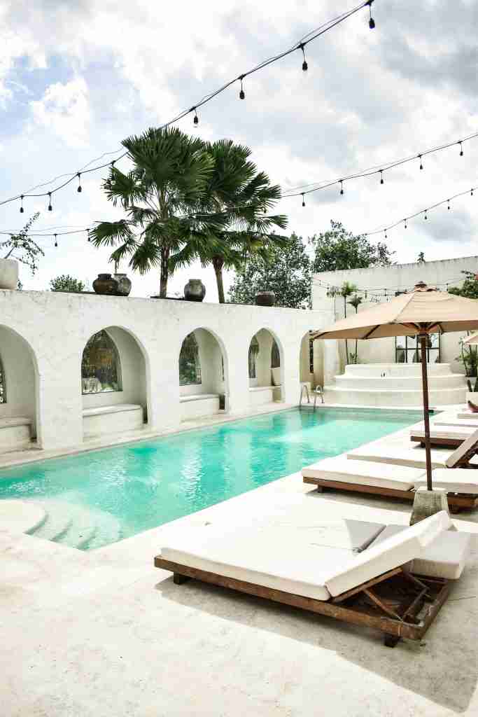 A serene pool surrounded by tropical plants at Hotel Sages, showcasing a relaxing and intimate ambiance. Keywords: Hotel Sages, pool, tropical, relaxing, Bali.