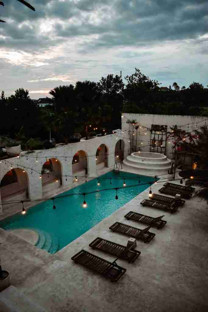 Refreshing swimming pool at Hotel Sages in Canggu, Bali, surrounded by lush tropical plants, offering a perfect spot to unwind and soak up the sun.